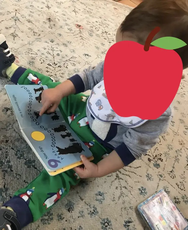 Exploring a board book on the rug